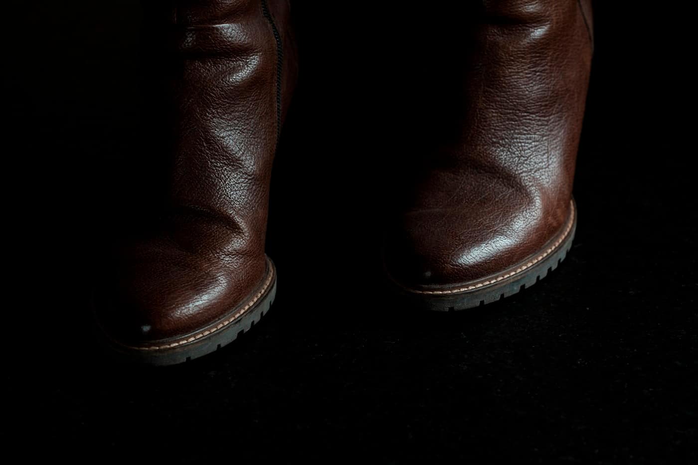 Leather boots in low light, the welted sole edge catching the light